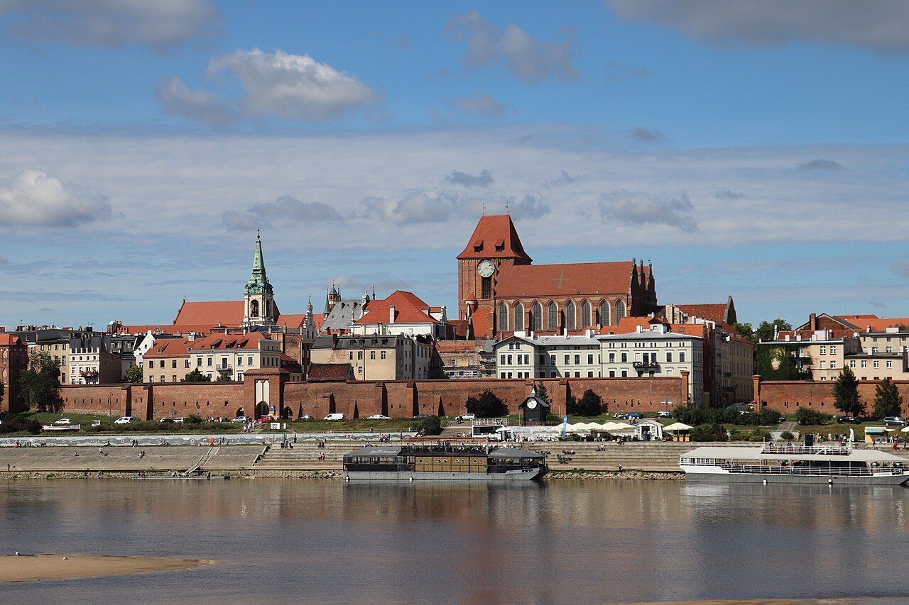 Panorama Toruně z druhého břehu Visly — cihlové městské hradby, gotická katedrála svatého Jana a věže Starého Města